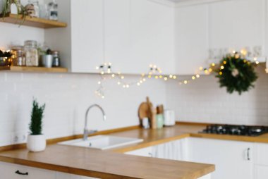 Arka plan bulanık beyaz modern mutfak İskandinav tarzı Noel için dekore edilmiştir. Şık şık beyaz seramik tuğla duvar, açık ahşap raflar, ahşap masa üstü