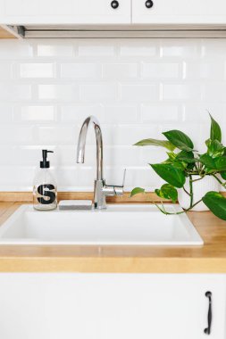 Arka plan beyaz lavabo sabun dispenseri ahşap tezgah ve beyaz seramik tuğla döşeme. Beyaz İskandinav mutfak detayları