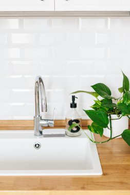 Arka plan beyaz lavabo sabun dispenseri ahşap tezgah ve beyaz seramik tuğla döşeme. Beyaz İskandinav mutfak detayları
