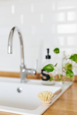 Arka plan beyaz lavabo sabun dispenseri ahşap tezgah ve beyaz seramik tuğla döşeme. Bambu bulaşık yıkama fırçası odak