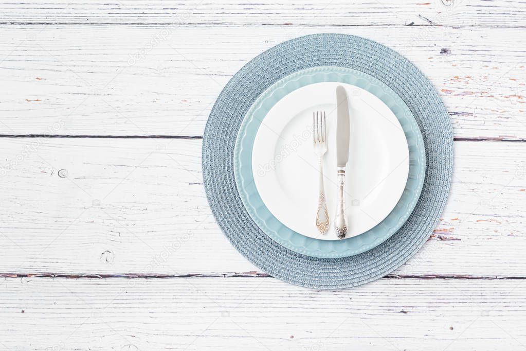 Spring table settings top view. Blue and white plate silver cutlery on wooden background place for text