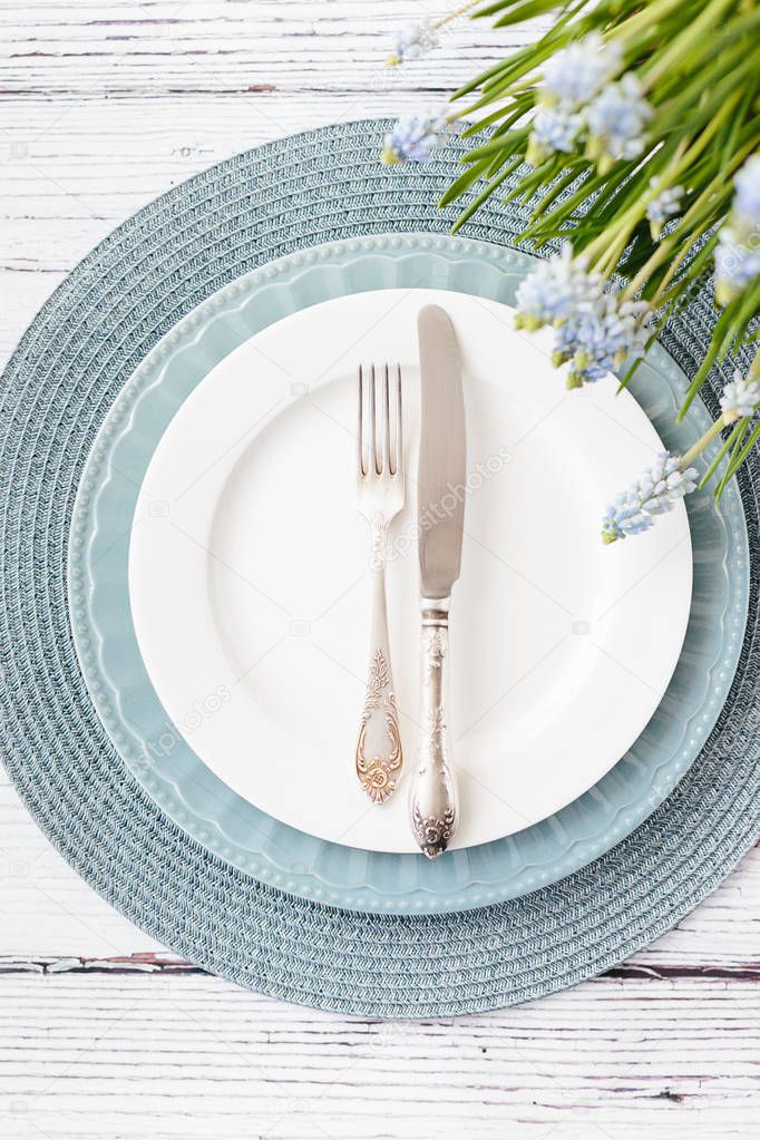 Spring table settings top view. Blue and white plate silver cutlery on wooden background place for text
