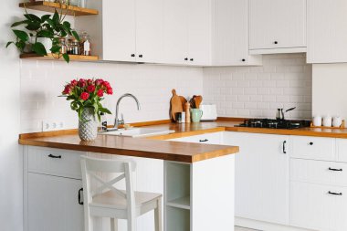 Lale buketi vazo daimi mutfak ahşap tezgah üzerinde. İskandinav tarzı modern beyaz mutfak u şeklinde.