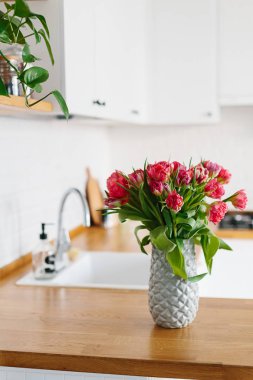 Lale buketi vazo daimi mutfak ahşap tezgah üzerinde. İskandinav tarzı modern beyaz mutfak u şeklinde.