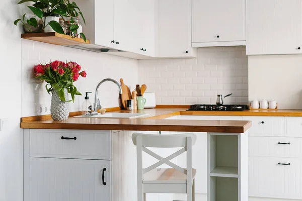 Lale buketi vazo daimi mutfak ahşap tezgah üzerinde. İskandinav tarzı modern beyaz mutfak u şeklinde.