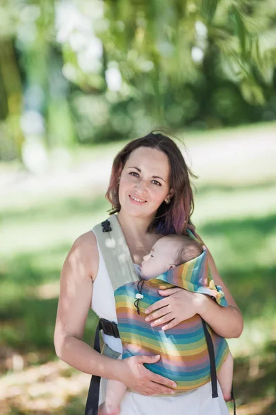 Informal mother carry baby girl in baby carrier in park — Stock Photo, Image