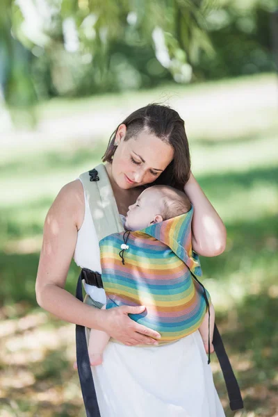 Madre informal llevar bebé niña en portabebés en el parque — Foto de Stock