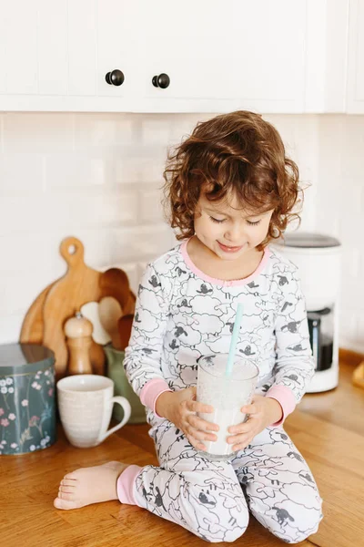 Little girl wearing pajamas drinking milk