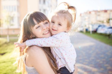 Anne küçük kızı tutar. Arka plan üzerinde yeni konut yapı.