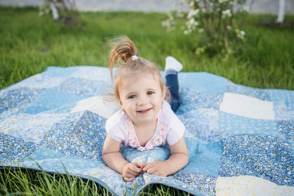 Маленька дівчинка лежить на килимку на траві — стокове фото