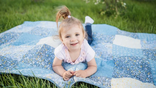 Маленька дівчинка лежить на килимку на траві — стокове фото