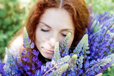 Kıvırcık kırmızı saçlı genç kadın acı bakla çiçekli