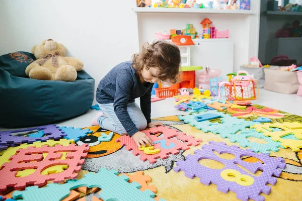 Liten flicka barn leker med siffror pussel — Stockfoto