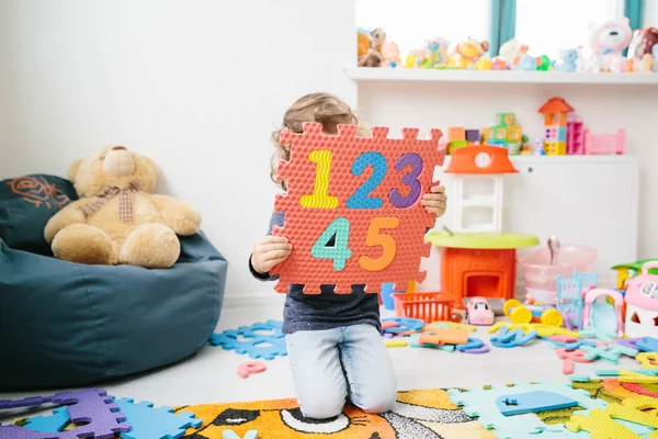 Liten flicka barn leker med siffror pussel — Stockfoto