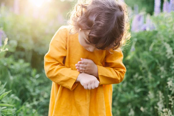 Чарівна дівчинка в гірчичній лляній сукні з сонечком серед квітів люпину — стокове фото
