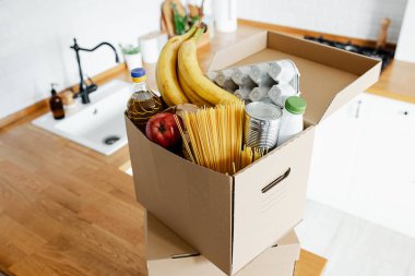 Mutfak masasındaki karton kutuda çeşitli gıda ürünleri. Yiyecek bağışları paylaşım konsepti. Yiyecek atıklarını azalt
