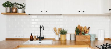 İskandinav tarzı beyaz mutfak manzarası mutfak ayrıntıları, ahşap masa üzerindeki bitkiler, beyaz seramik tuğla duvar arka planı. Sürdürülebilir çevre dostu mutfak.