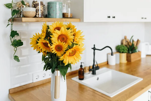 Mutfakta vazoda ayçiçeği buketi, seçici odaklanma. Arka planda İskandinav tarzı temiz, basit, modern bir mutfak.