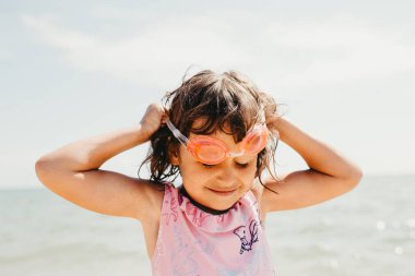 Tek boynuzlu atlarla pembe mayo giyen küçük kız denizde yüzme gözlüğü takıyor. Tatil zamanı.