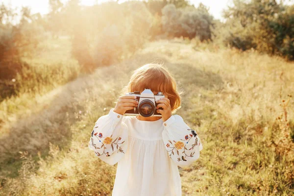 Nakış işlemeli bluz giyen küçük bir kız, eski fotoğraf makinesiyle fotoğraf çekimi yaz günbatımı, pozitif titreşimler, basit kırsal yaşam. Atmosferik resim