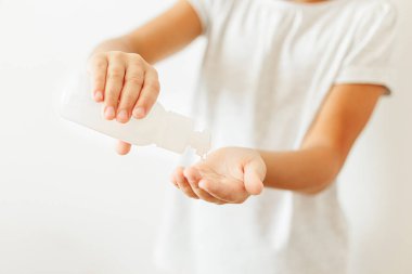 Dezenfekte eden eller. Çocuk, virüs salgınını önlemek için beyaz ışıkta eline dezenfeksiyon jeli alıyor. Grip hastalığının önlenmesi. Ellerini düzgün bir şekilde temizleyip dezenfekte etmek..