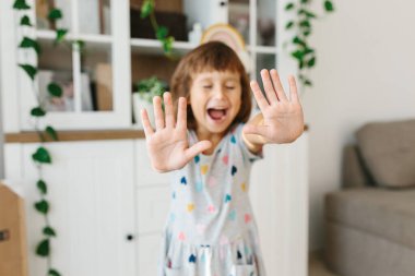 Dezenfekte eden eller. Dezenfeksiyondan sonra el ele tutuşan bir kız çocuğu virüs salgınını önlemek için oturma odasının arka planına alkollü jel sürüyor. Seçici odak elleri