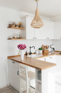 İskandinav tarzında temiz, basit, modern mutfağa bakın. Mutfak detayları, ahşap masa. Masadaki paskalya Michaelmas papatyası.