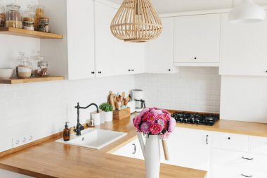 İskandinav tarzında temiz, basit, modern mutfağa bakın. Mutfak detayları, ahşap masa. Masadaki paskalya Michaelmas papatyası.