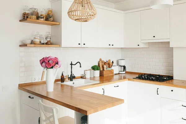 İskandinav tarzında temiz, basit, modern mutfağa bakın. Mutfak detayları, ahşap masa. Masadaki paskalya Michaelmas papatyası.