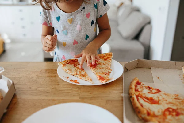 Happy time of eating concept. Kids girl eating pizza at home. Adorable childr enjoy eating pizza with a very happy emotional expressions of face