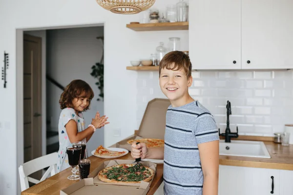 Happy time of eating concept. Kids boy and girl eating pizza at home. Two Adorable children enjoy eating pizza with a very happy emotional expressions of faces and postures.