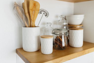 Kitchen shelves with various white ceramic and glass jars. Open shelves in the kitchen. Kitchen interior ideas. Eco friendly kitchen, zero waste home concept clipart