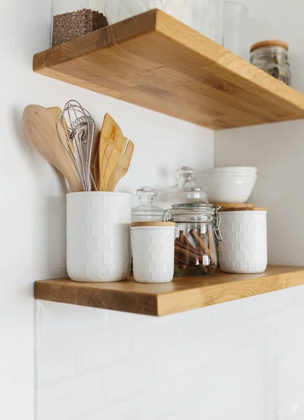 Kitchen shelves with various white ceramic and glass jars. Open shelves in the kitchen. Kitchen interior ideas. Eco friendly kitchen, zero waste home concept