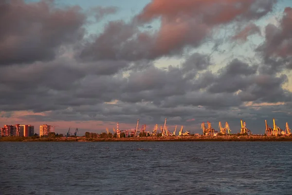Zee landschap met scheepswerf kranen in zonsondergang licht — Stockfoto