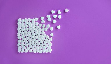 Kalpleri uçup mor bir kağıt arka plan üzerinde beyaz şeker şekerlerinden yapılmış kare