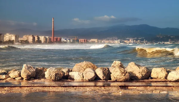 Olas espumosas del mar Alboraniano en primer plano y la ciudad de Málaga al pie de las montañas en el fondo en un clima tormentoso. España. Andalucía . — Foto de Stock