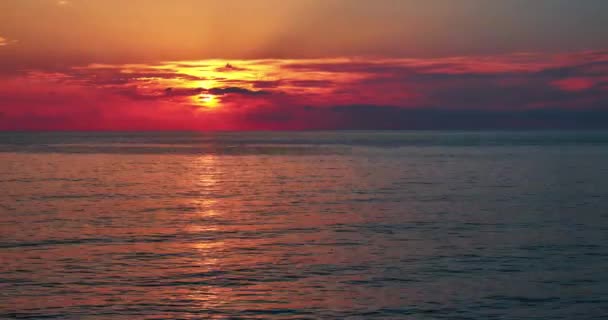 Sonne bewegt sich durch Wolken hinunter zum Meer und macht rotes Licht 4k — Stockvideo