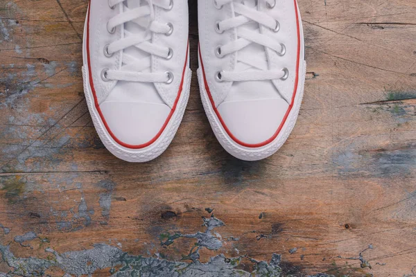 A pair of white canvas shoes or sneakers on a wooden background, toned vintage