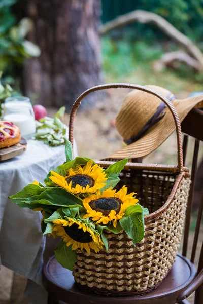 Sunflower Helianthus annuus in a basket on the chair with a hat at the background