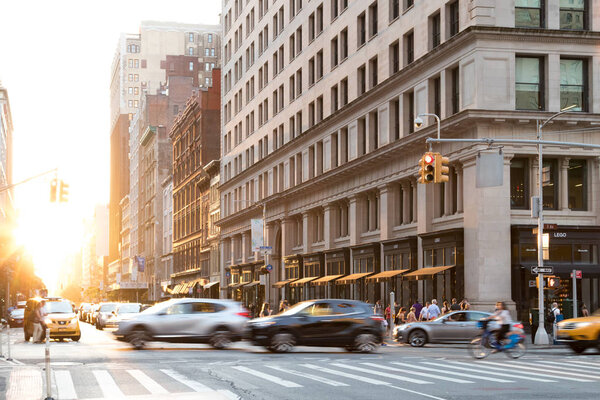 NEW YORK CITY - JUNE, 2018: Cars speed down 5th Avenue with the glow of sunlight reflecting on the background buildings in Manhattan.