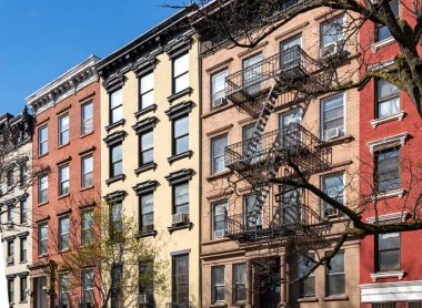 New York 'ta Manhattan' ın doğu köyündeki Tompkins Meydanı Parkı boyunca 10. caddedeki renkli eski binalar.