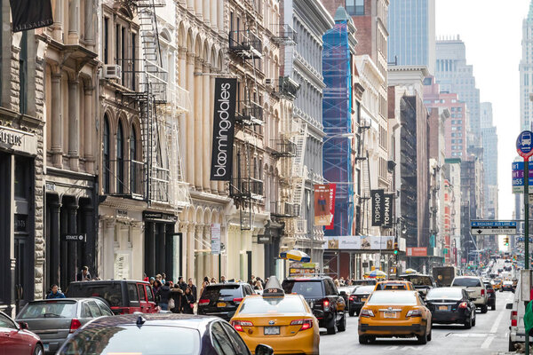 NEW YORK CITY, CIRCA 2018: Traffic drives down Broadway as crowds of people walk along the sidewalks of SoHo on a busy day in Manhattan, NYC.
