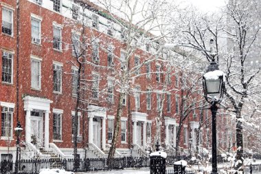 Snow covered winter street scene with old buildings along Washington Square Park in Manhattan New York City NYC clipart