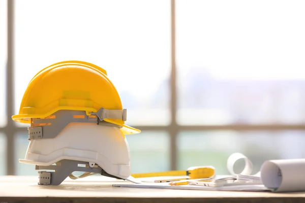 White and yellow safety helmet in construction site, light from big window in background