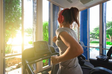 Spor salonunda koşu bandı egzersiz aletleriyle koşan bir kadın..