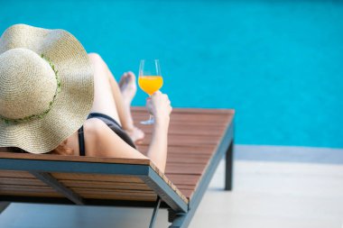 Yüzme havuzunun yanında bir kadın oturuyor.