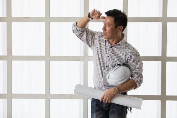 Asiático senoir engenheiro segurando branco capacete de engenharia e rolo — Fotografia de Stock