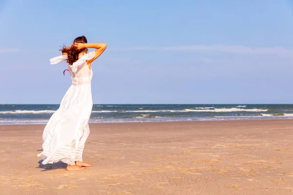 Donna in abito bianco sulla spiaggia — Foto Stock