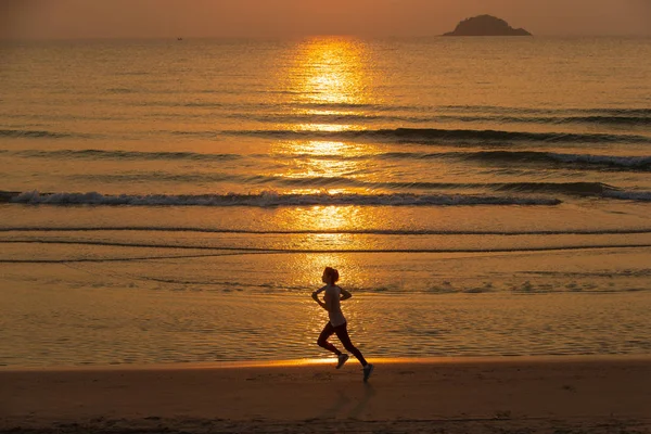 Femme courant sur la plage au lever du soleil — Photo