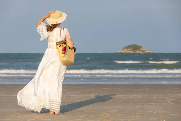 Kvinna bär hatt och hålla väska på stranden — Stockfoto